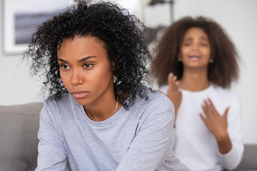 Black angry mother and apologizing daughter on background