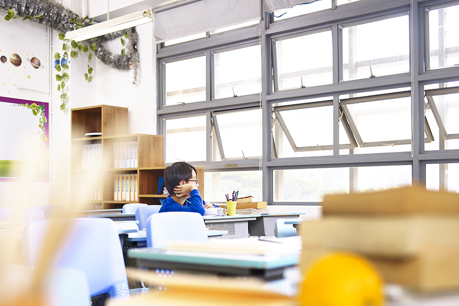 asian elementary school student sitting alone in classroom