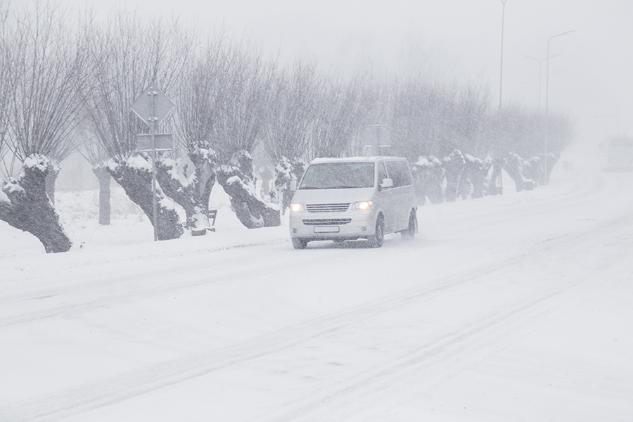 Limbazi, Latvia, Europe. January 24, 2018. Poor visibility in heavy snow storm on road. Minibus driving slowly in dangerous weather day. Cataclysm of nature.. Traffic in blizzard.