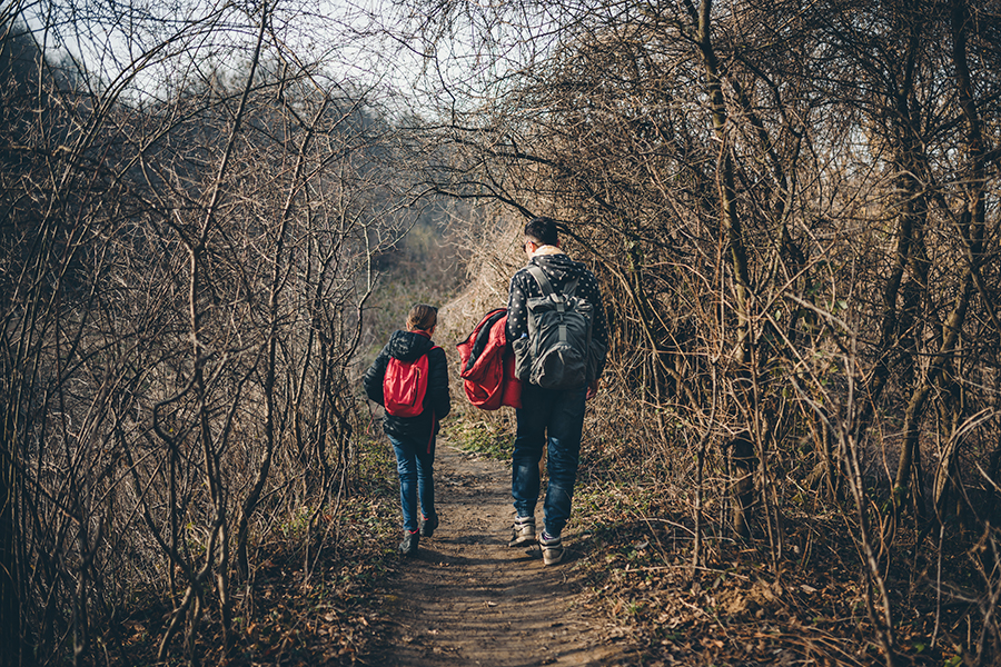 Father and daughter hiking on forest trail