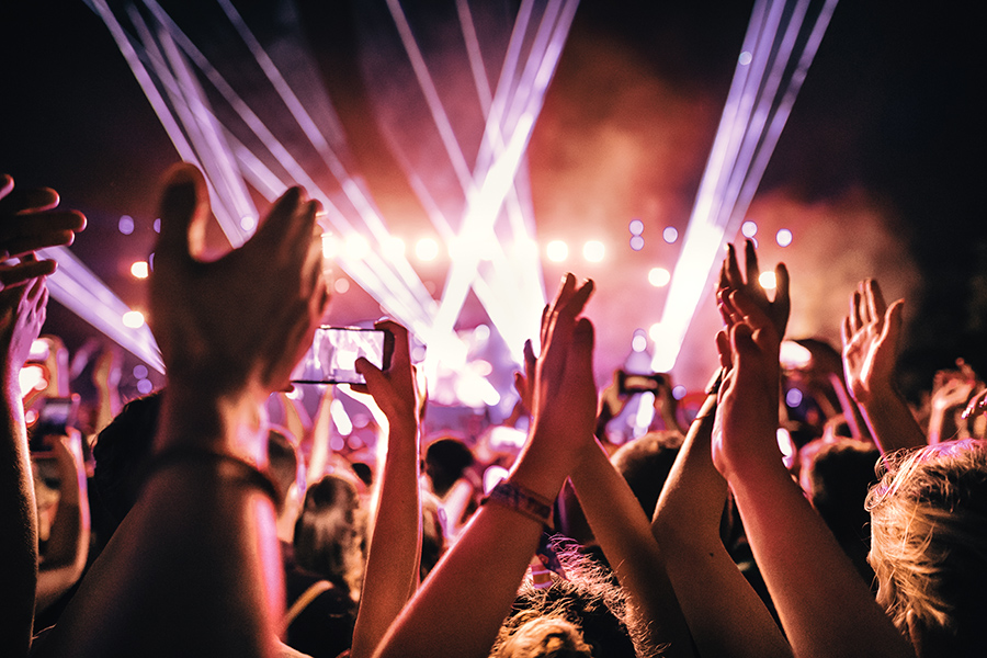 strong female women: life should be like a taylor swift concert. Fans waving hands and holding up phones, looking toward bright concert stage.