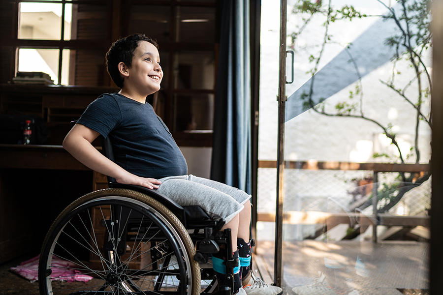 young disabled boy in his wheelchair looking out at his yard with a smile. looking toward the future with a child with disabilities