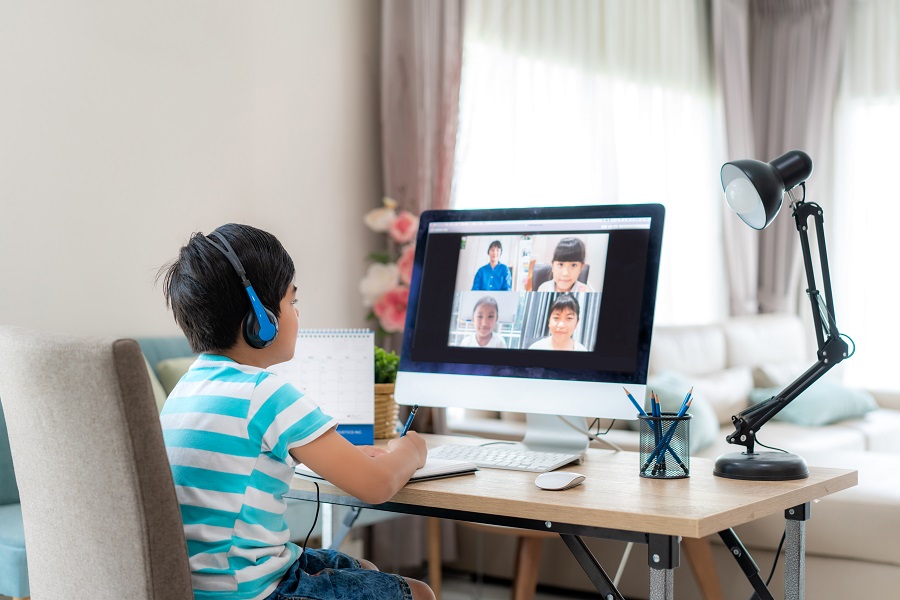 signs of dyslexia. a young boy 8-10yrs old is sitting at a desk in his living room at home, participating in virtual learning with several classmates.