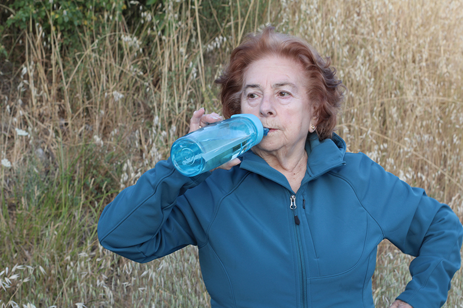 Senior woman drinking water after jogging