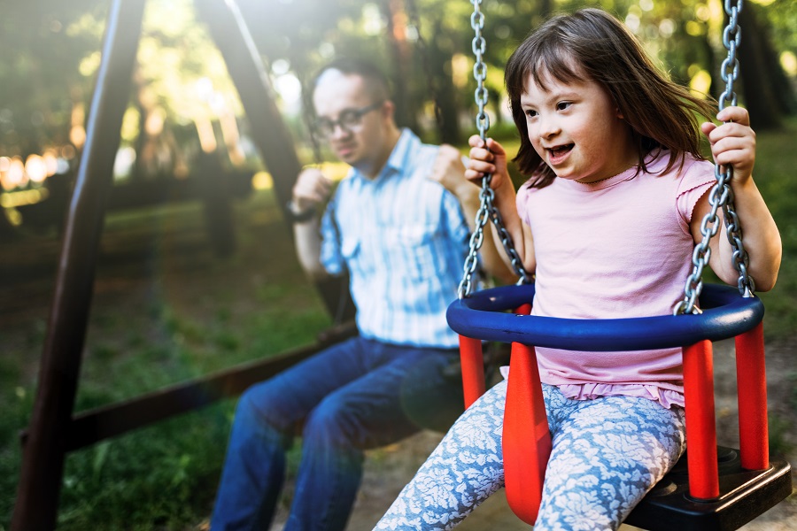 Portrait of man and girl with down syndrome swinging