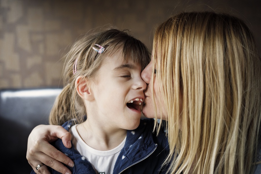 Mother kissing daughter with impaired vision