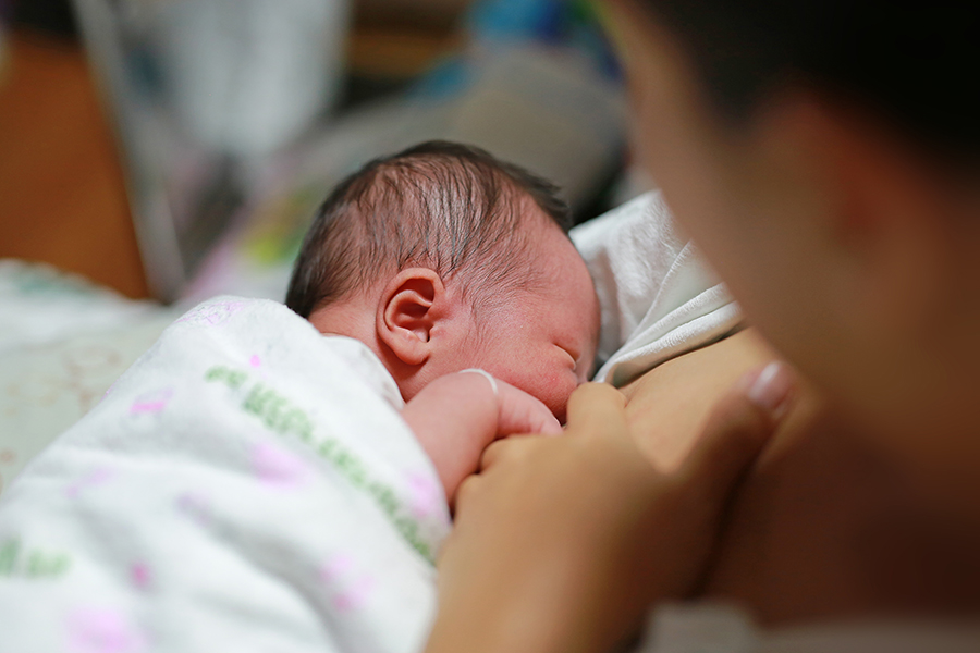 Young mother breast feeding her newborn child.