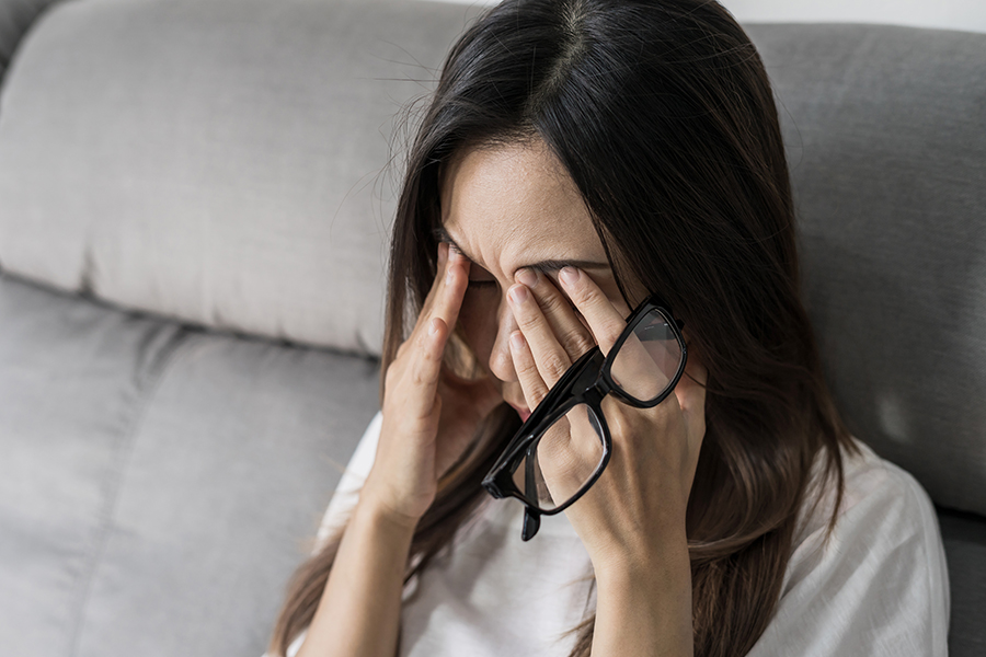 Young woman take off her glasses and sitting on sofa